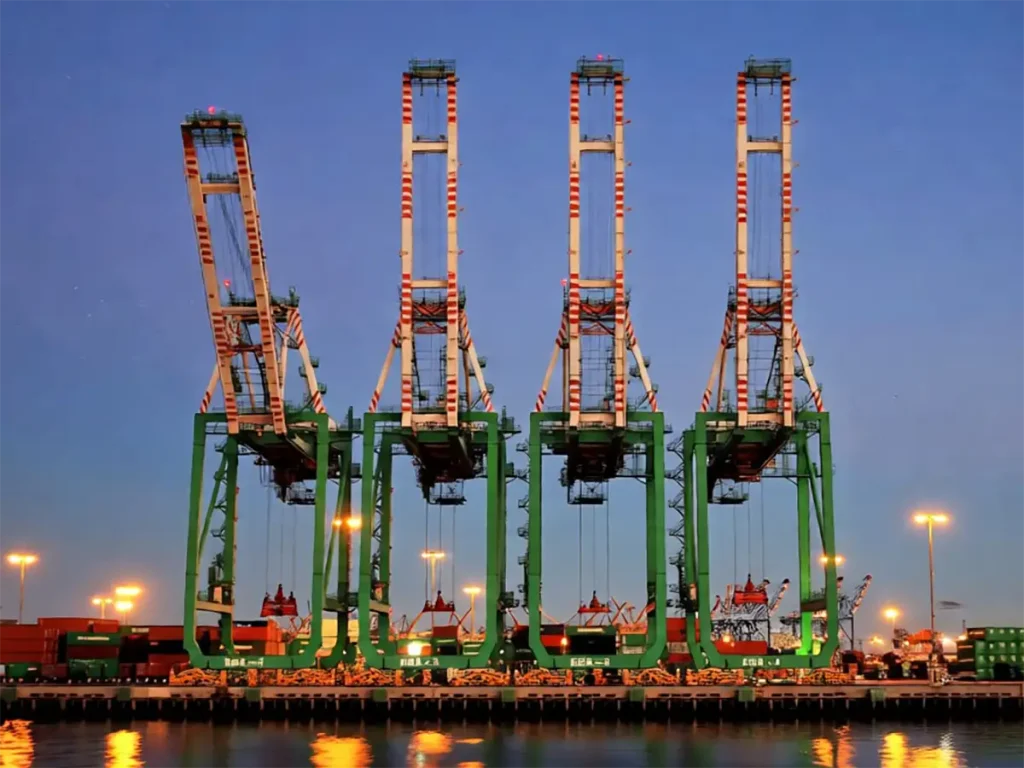 Container gantry cranes at a shipping port at dusk